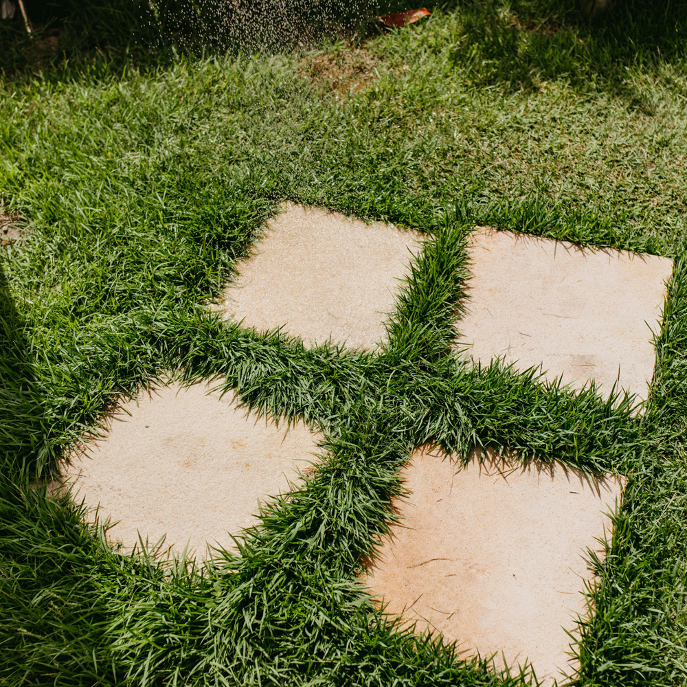 Onderhoudsvriendelijke tuin Tegels in een grasveld